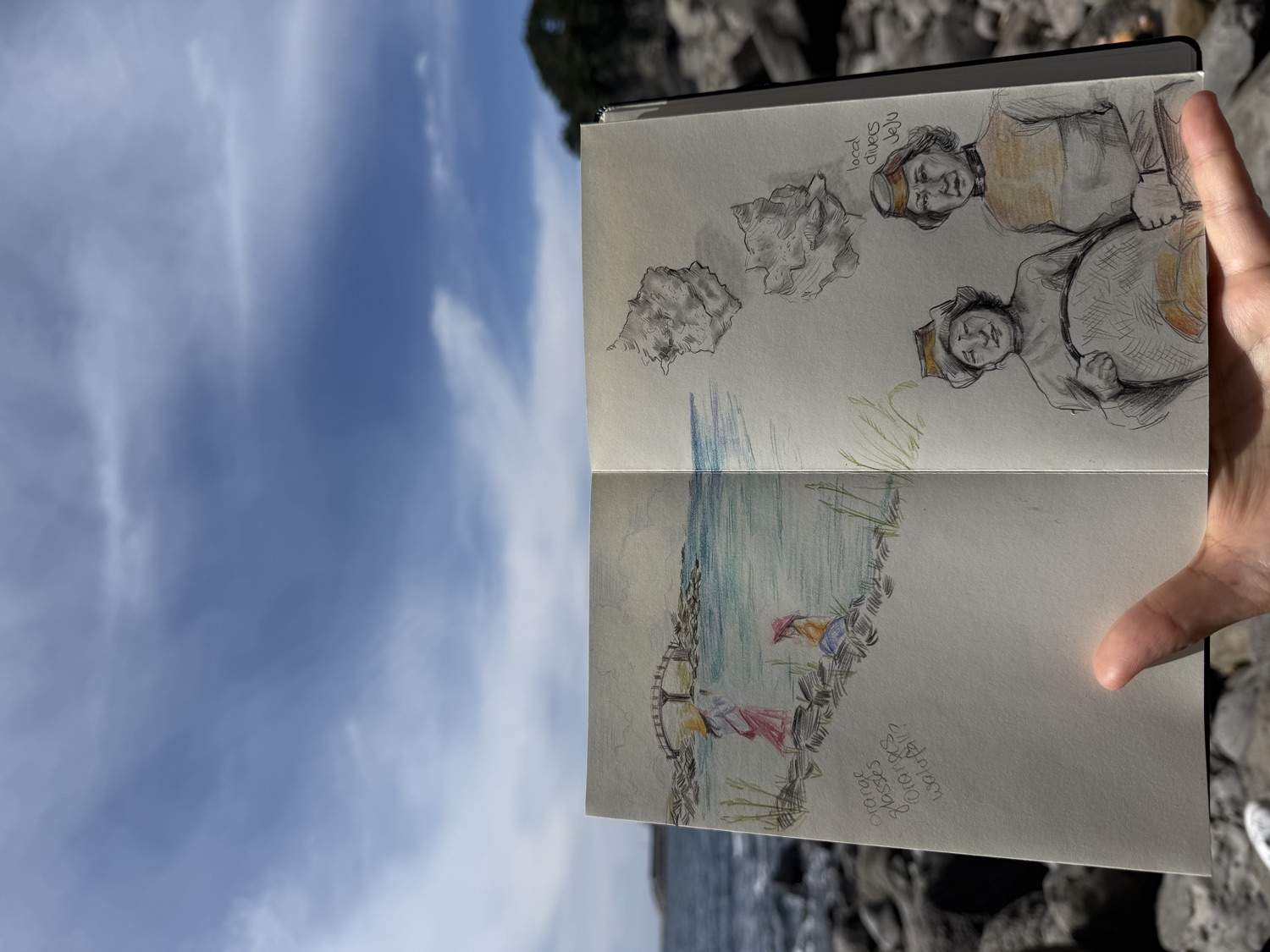 A guest's sketchbook held up against the Jeju sea